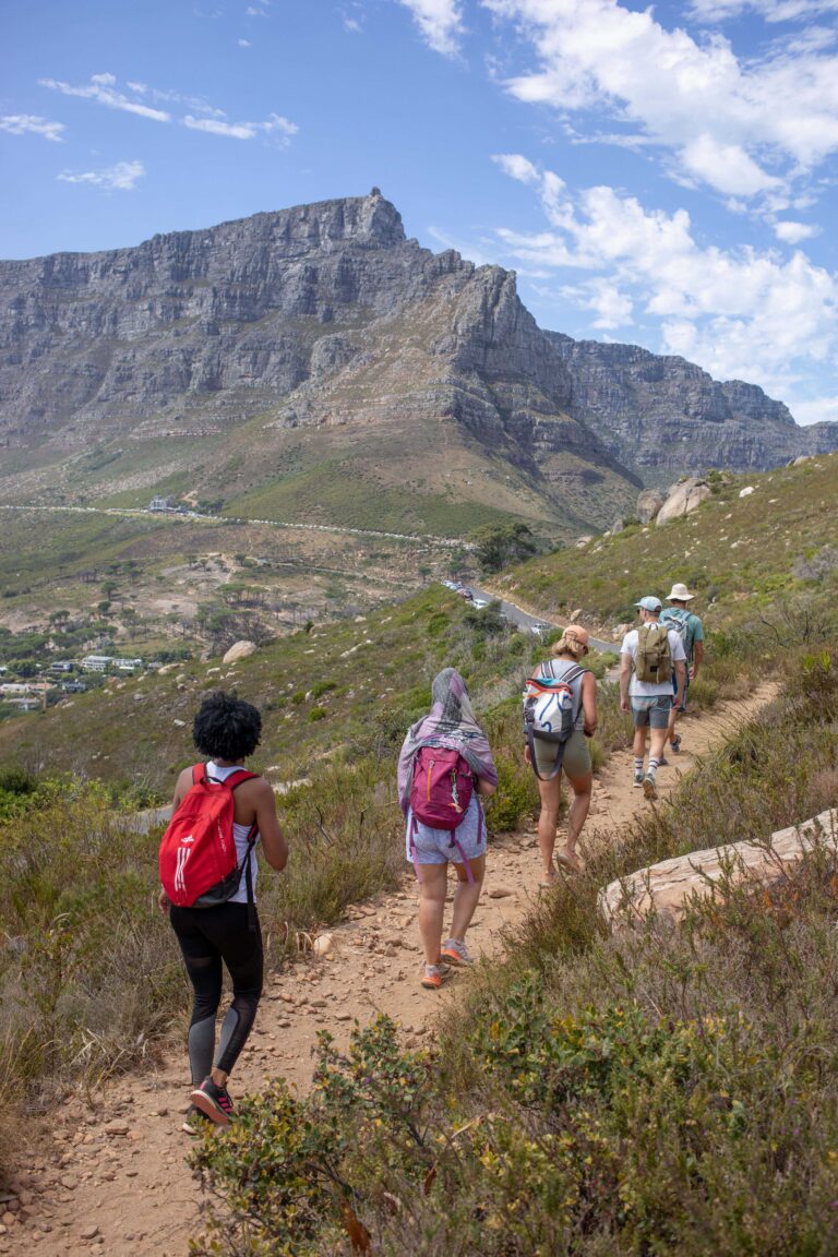 Walkers on a mountain trail with Table Mountain behind them