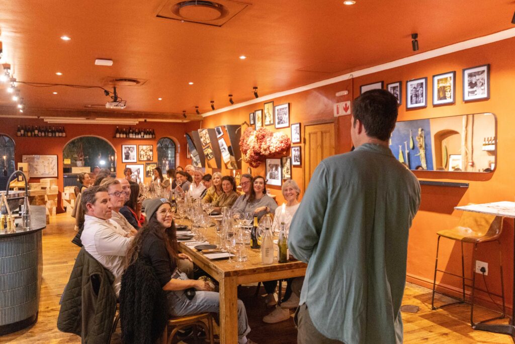 Guests at a long dinner table listening to their storyteller
